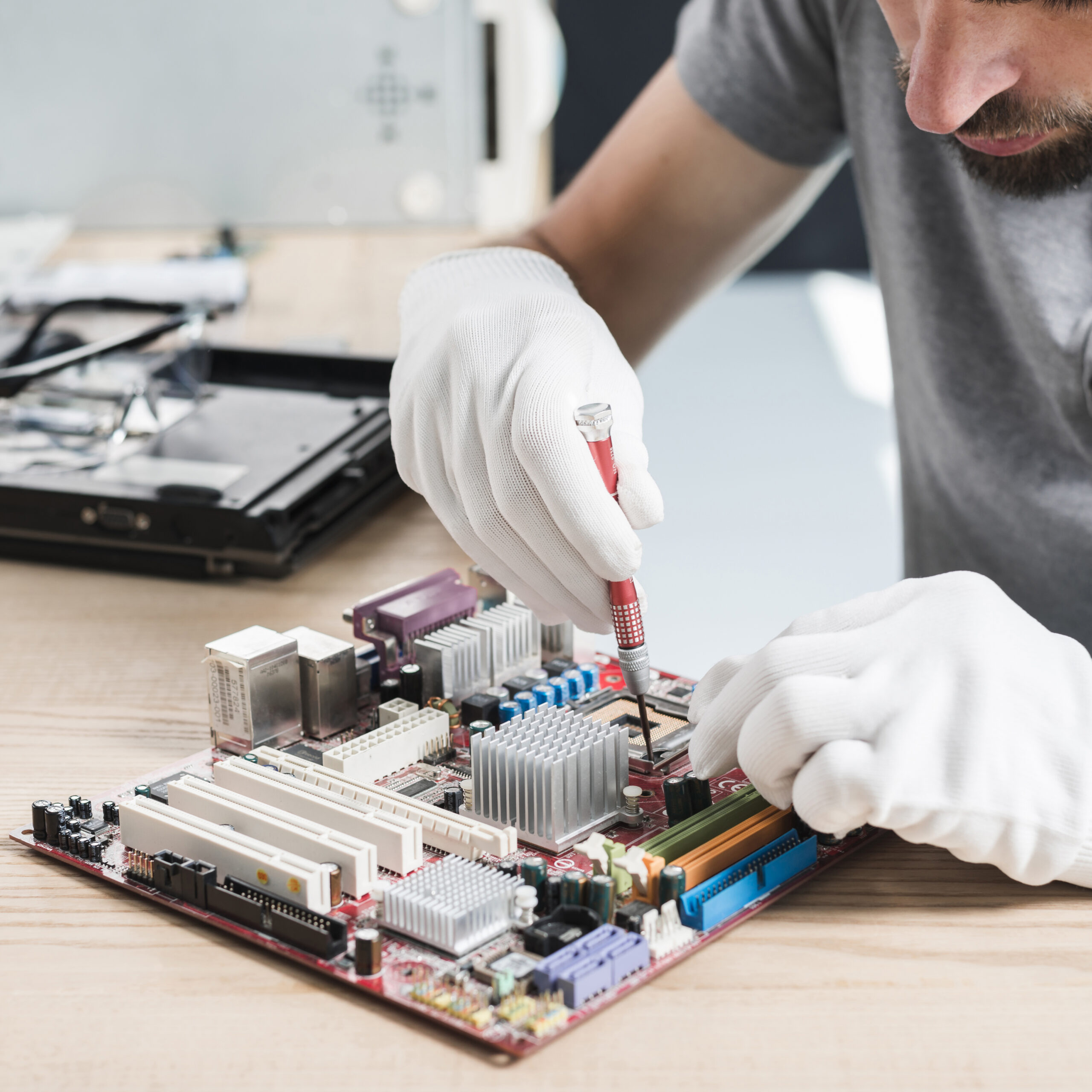 close up male technician hand repairing computer motherboard wooden desk